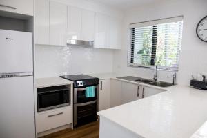 a kitchen with white cabinets and a stove top oven at 2 Bedroom Renovated Townhouse, Walk to Noosa River in Noosaville