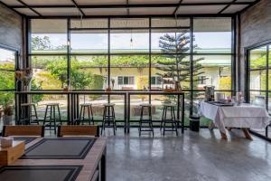 a large room with tables and chairs and large windows at บ้านสวนวารินทร์ รีสอร์ท in Pak Chong