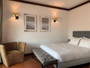 a bedroom with a bed and a chair and two windows at Charming old town in Cascais