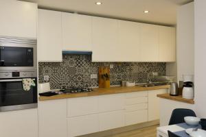 a kitchen with white cabinets and a microwave at Love apartment Beco Torto, Cascais in Cascais