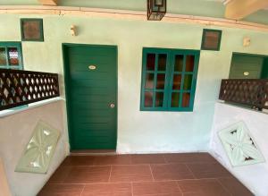 two green doors on a building with a tile floor at Sabak Awor Resort in Muar