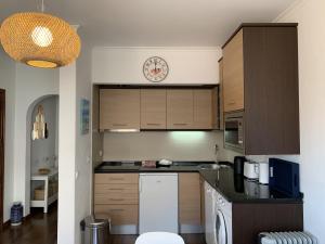 a kitchen with wooden cabinets and a clock on the wall at Relaxing apartment in the heart of Cascais in Cascais