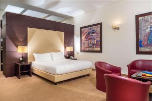 a bedroom with a bed and a desk and two chairs at Europalace Hotel, BW Signature Collection in Monfalcone