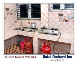 a tiled kitchen with a stove and a sink at Hotel orchard inn in Velankanni