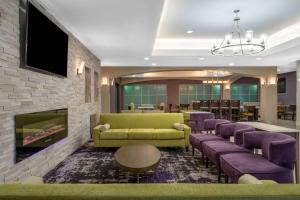 a waiting room with a green couch and purple chairs at La Quinta by Wyndham Atlanta Stockbridge in Stockbridge