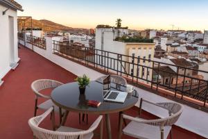 een tafel en stoelen op een balkon met een laptop bij EL CIELO DE CÁCERES in Cáceres