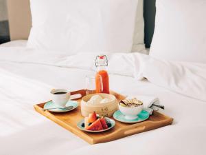 a tray with coffee and fruit on a bed at Pullman Sharjah in Sharjah