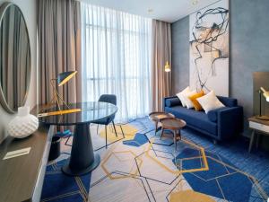 a living room with a blue couch and a glass table at Pullman Sharjah in Sharjah