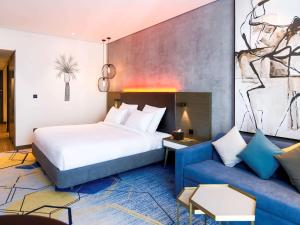a hotel room with a bed and a couch at Pullman Sharjah in Sharjah
