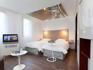 a hotel room with two beds and a television at ibis Styles Lille Aéroport in Lesquin