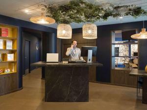 a man talking on a microphone at a desk in an office at Aparthotel Adagio Annecy Centre in Annecy