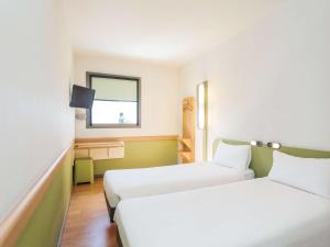 Una habitación de hotel con dos camas y una ventana. en Ibis Budget Madrid Vallecas, en Madrid