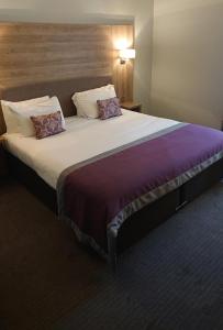 uma cama grande num quarto de hotel com duas almofadas em The Feathers em Pocklington