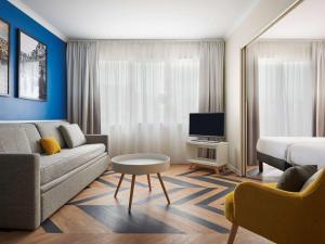 - un salon avec un canapé et un lit dans l'établissement Aparthotel Adagio Porte de Versailles, à Paris