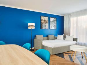 - un salon avec un lit et un mur bleu dans l'établissement Aparthotel Adagio Porte de Versailles, à Paris