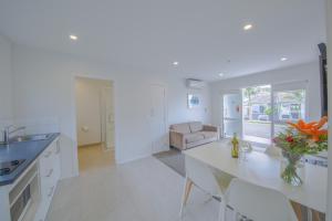 a white kitchen with a table and a couch at Sylvia Park Motel in Auckland