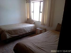 1 dormitorio con 2 camas y ventana en Unit 6 Villa Marina, en Hibberdene