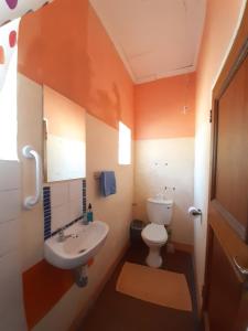 an orange bathroom with a toilet and a sink at Elkes Guesthouse in Nieu-Bethesda +4 photos