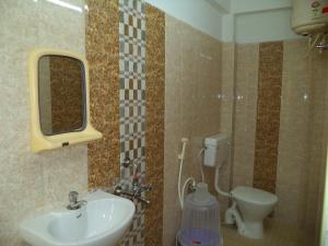 a bathroom with a sink and a toilet and a mirror at Samrat Guest House KK Nagar in Chennai