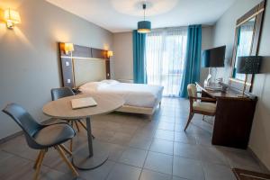 a hotel room with a bed and a table with a laptop on it at Hôtel Résidence Les Pins Galants in Tournefeuille