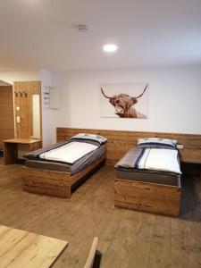 two beds in a room with a picture of a cow on the wall at Hansmayrgut in Waizenkirchen