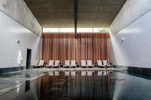 um quarto com uma piscina com cadeiras brancas e água em Axis Viana Business & SPA Hotel em Viana do Castelo mais 37 fotografias