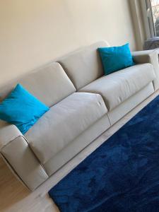 białą kanapę z dwoma niebieskimi poduszkami w obiekcie ViCo HomeSuite w mieście Milazzo