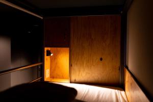 Habitación oscura con cama con pared de madera. en Wise Owl Hostels River Tokyo en Tokio