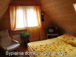 a bedroom with a bed and a window and a chair at Domek regionalny Busola in Zakopane