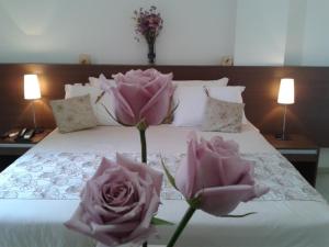 zwei rosa Rosen auf dem Bett in der Unterkunft Hotel Cristal in Turmalina