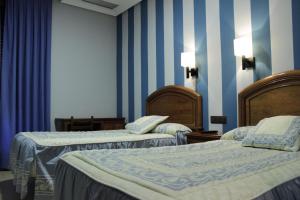 two beds in a room with blue and white stripes at Hostal Ana Belen in Madrid