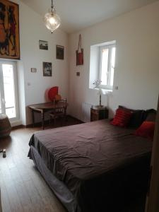 a bedroom with a bed and a table and two windows at L'Escale Bellevue in Blaye