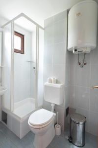 y baño blanco con aseo y ducha. en Hostin Gajac en Novalja