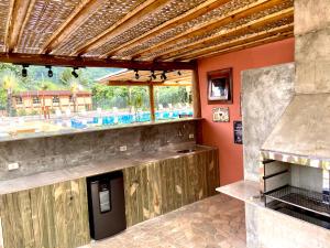 an outdoor kitchen with a bar and a grill at Maresias flat mata azul 2 in Maresias
