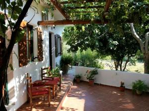 a patio with chairs and a building with trees at Hariklia Rent Rooms in Zaros