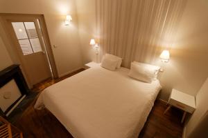 - une petite chambre avec un lit blanc et 2 oreillers dans l'établissement Appart'Hôtel Sainte Trinité, à Troyes