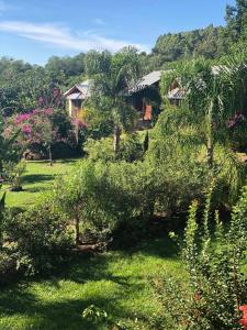 a garden with trees and bushes in front of a house at RANCHO COSTEIRO AGROTURSIMO E BALNEARIO E PESQUEIRO in Pôrto Xavier