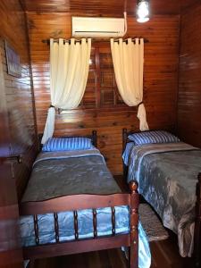 two beds in a room with wooden walls and curtains at RANCHO COSTEIRO AGROTURSIMO E BALNEARIO E PESQUEIRO in Pôrto Xavier +32 photos