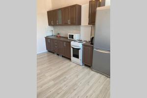 La cuisine est équipée de placards bruns et d'un réfrigérateur blanc. dans l'établissement Новая квартира в новом доме, à Karaganda