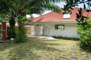 Casa blanca con techo rojo en Ixora Villa, en Anse Royale