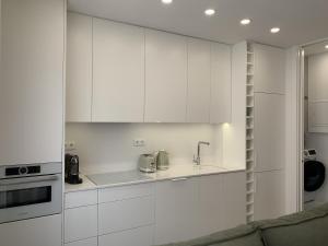 a white kitchen with white cabinets and a sink at Cascais Downtown Premium Apartment 1 in Cascais