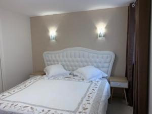 1 cama blanca con 2 almohadas y 2 luces en la pared en Coeur d'Alsace Colmar Vignobles Ouest avec terrasses, en Wintzenheim