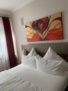 a bedroom with a white bed with a painting on the wall at Hotel Isabella in Frankfurt