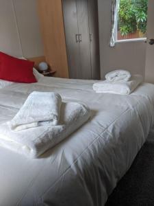 a white bed with towels on top of it at Caravan nearby Hastings Coghurst Hall Park in Guestling