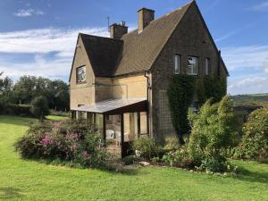 a large brick house with a roof at Beautiful 3 bedroomed Cotswolds Farmhouse in Andoversford