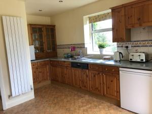 d'une cuisine avec des placards en bois, un évier et une fenêtre. dans l'établissement Beautiful 3 bedroomed Cotswolds Farmhouse, à Andoversford