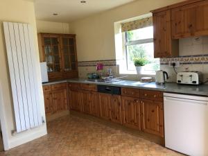 a kitchen with wooden cabinets and a sink and a window at Beautiful 3 bedroomed Cotswolds Farmhouse in Andoversford