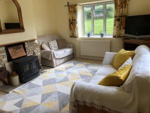 a living room with a couch and a fireplace at Beautiful 3 bedroomed Cotswolds Farmhouse in Andoversford