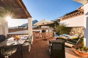 a patio with tables and chairs and an umbrella at Townhouse Sleeps 6 with Private Pool in Gaucín