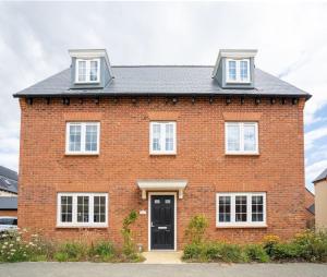 比斯特的住宿－Lovely 5-Bed House in centre of Bicester Village，一张红砖房子的图象,有一道黑门